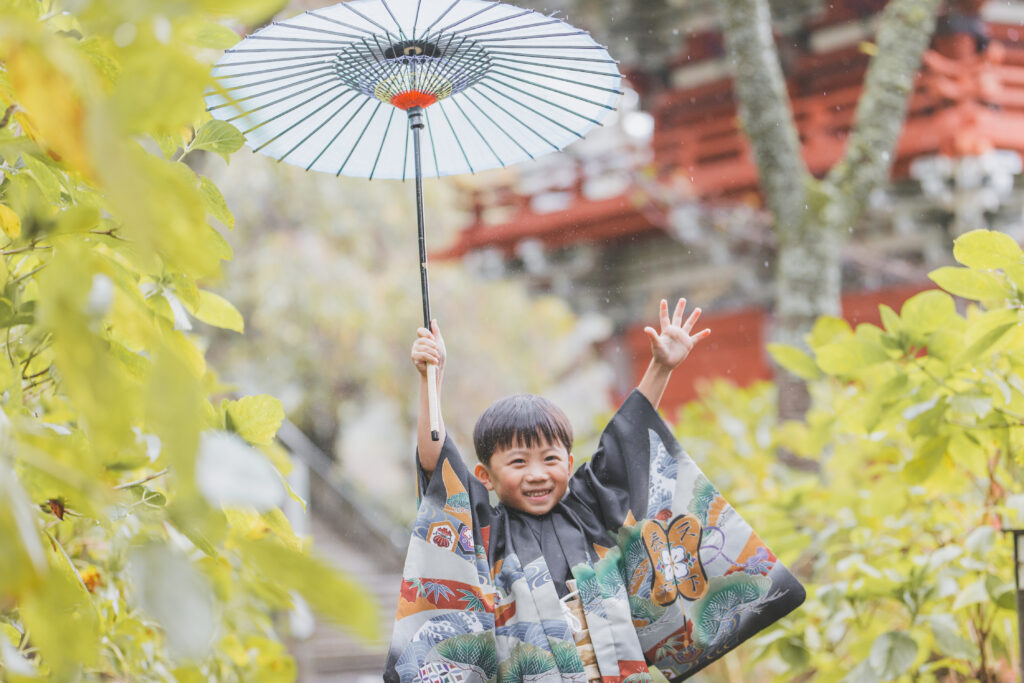 傘を持って笑う七五三の兄妹(雨の日の撮影)