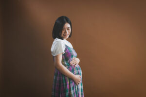 お腹にそっと手を添える夫婦のマタニティフォト。小山市写真スタジオでの撮影