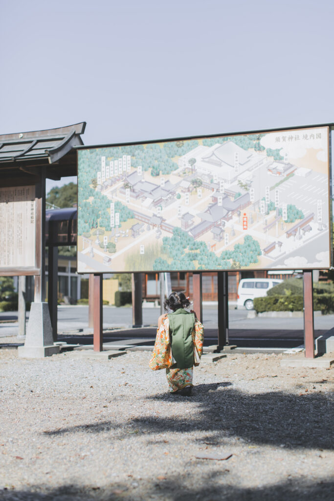 須賀神社の案内マップを見て黄昏れる七五三の3歳女の子