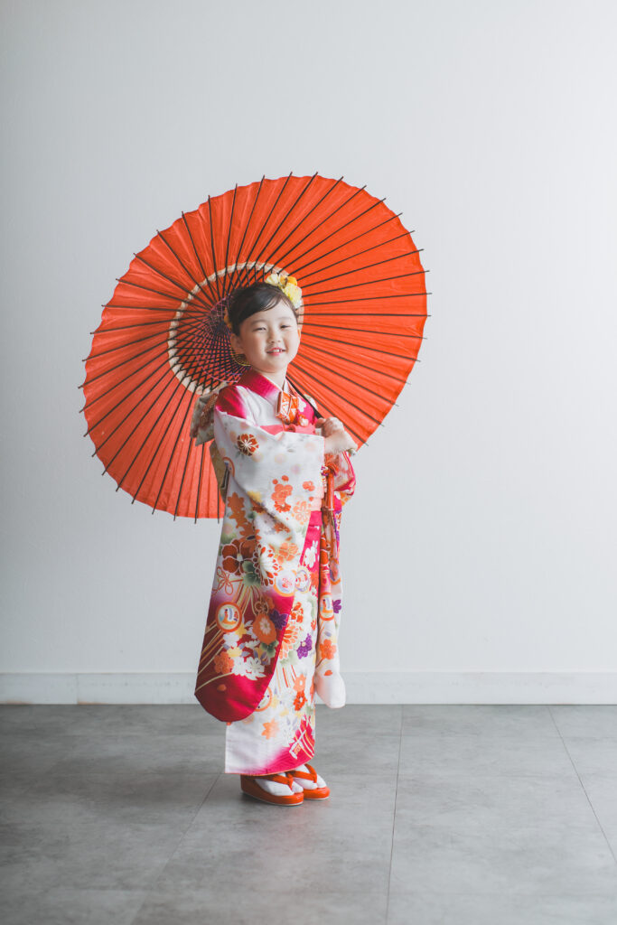 和傘を持って落ち着いた雰囲気で立つ七五三の記念写真