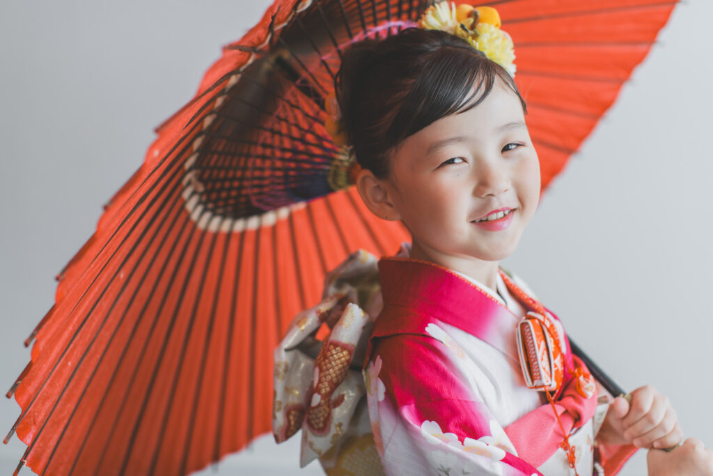 和傘を持って落ち着いた雰囲気で立つ七五三の記念写真