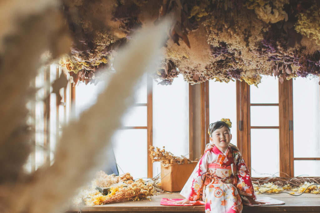 撮影セットで椅子に座り、柔らかい笑顔を見せる7歳女の子