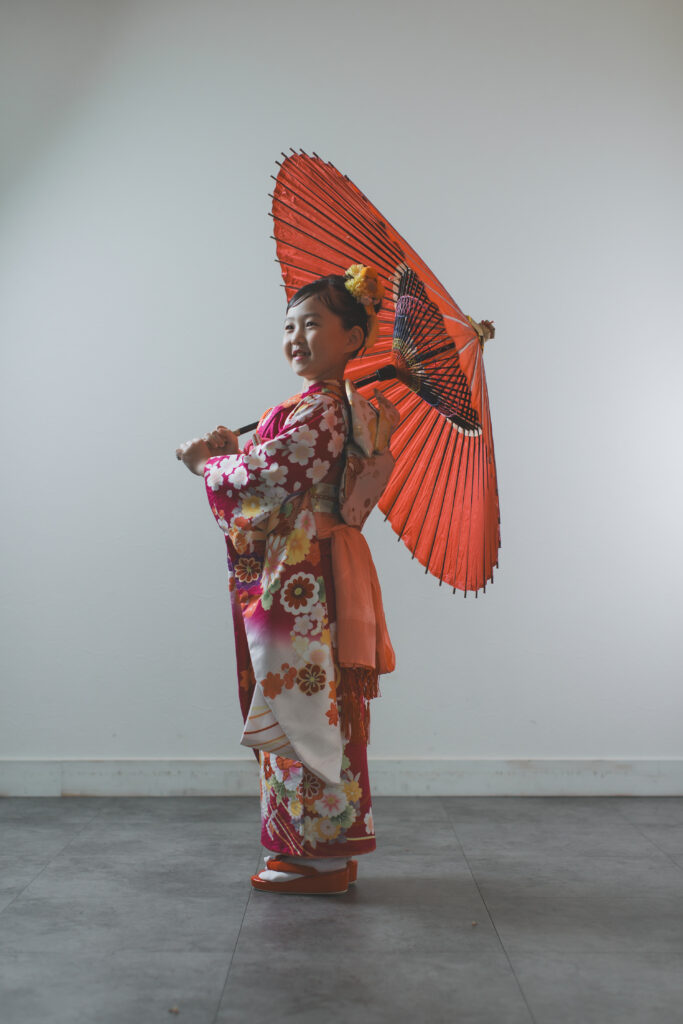 和傘を持って落ち着いた雰囲気で立つ七五三の記念写真